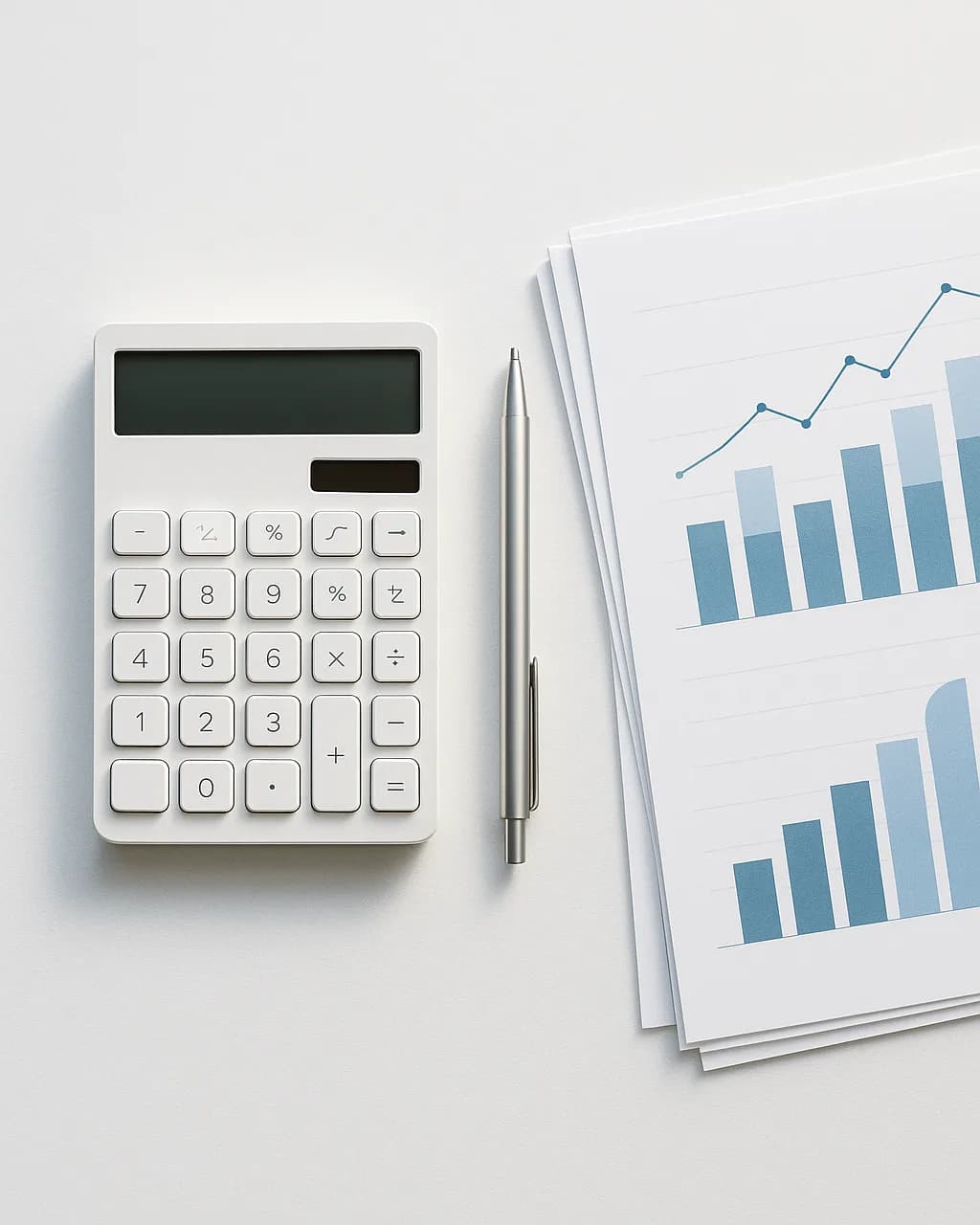Calculator, pen and printed bar charts laid out on a white desk